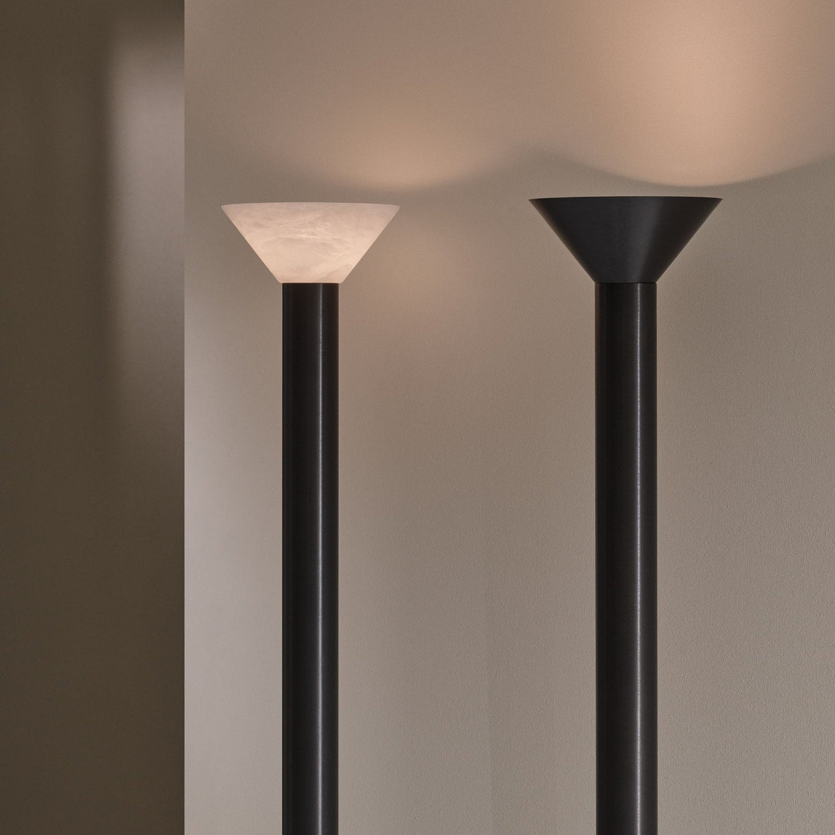 Two black floor lamps with white and black lampshades on a plain background